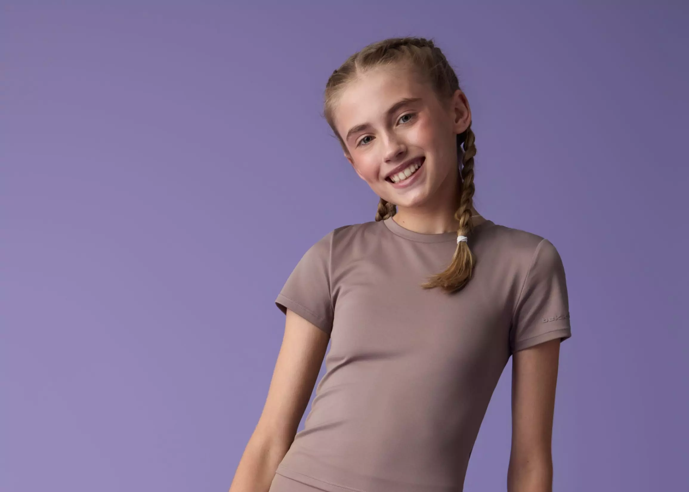 Niña sonriente con trenzas llevando camiseta deportiva marrón de manga corta Pepco.
