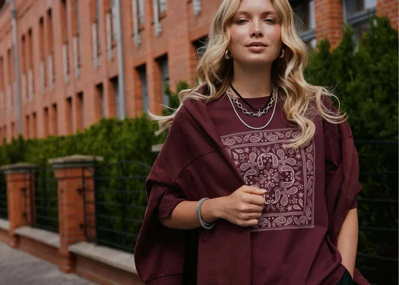Pepco burgundy sweatshirt with paisley print detail, styled with layered silver necklaces and bracelet.