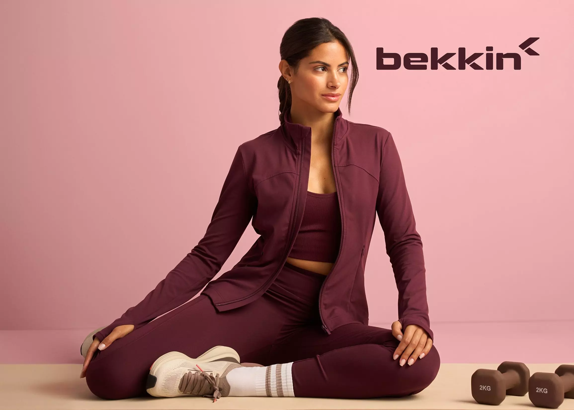 Žena v bordovej športovej súprave bekkin sedí v Pepco pri cvičebných čintiach.