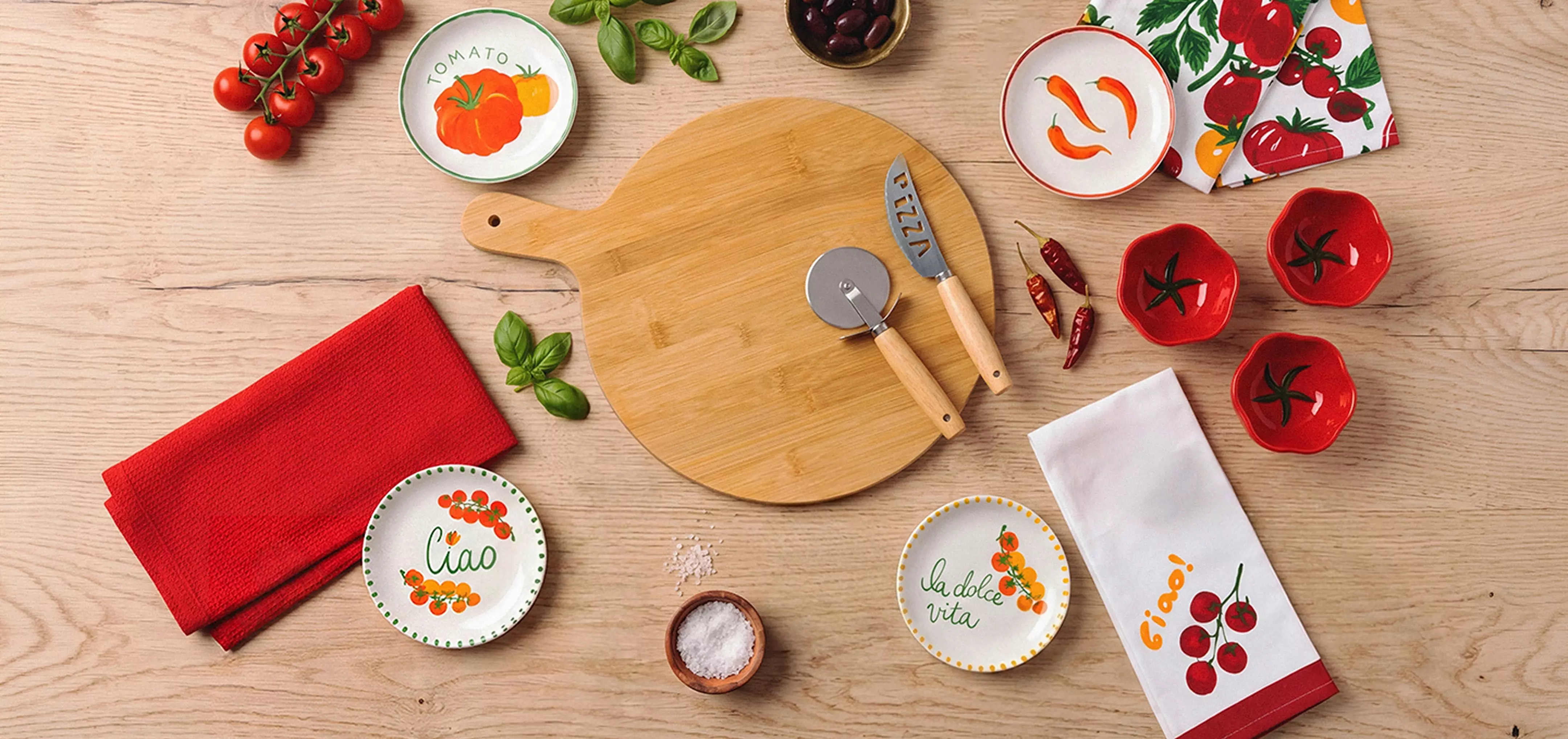 Pepco Italian-themed kitchen accessories including bamboo chopping board, pizza cutter, decorative plates and tea towels.