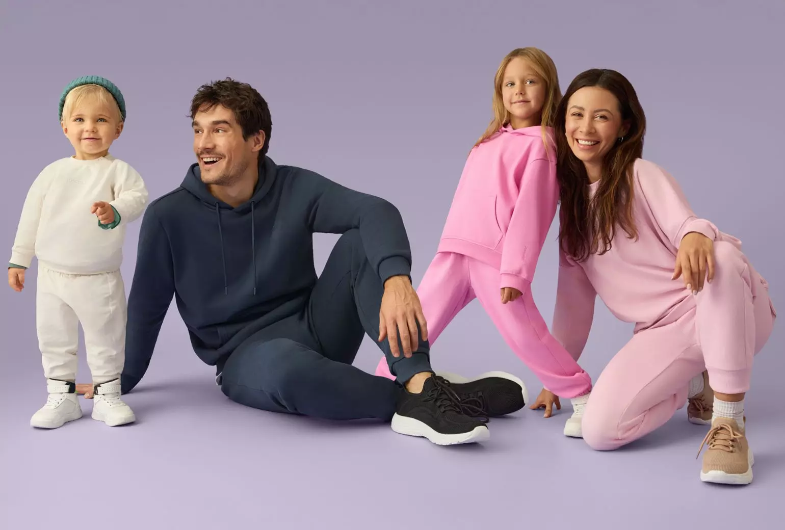 Rodzina w wygodnych dresach Pepco - biały zestaw dla malucha, granatowy dla mężczyzny oraz różowe komplety dla dziewczynki i kobiety.