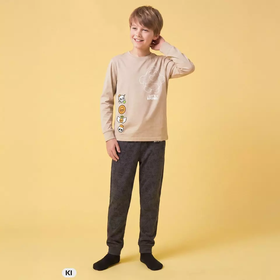 Junge trägt Pepco Pyjama-Set in Beige mit Line Brown Motiv und dunkelgrauer Hose.