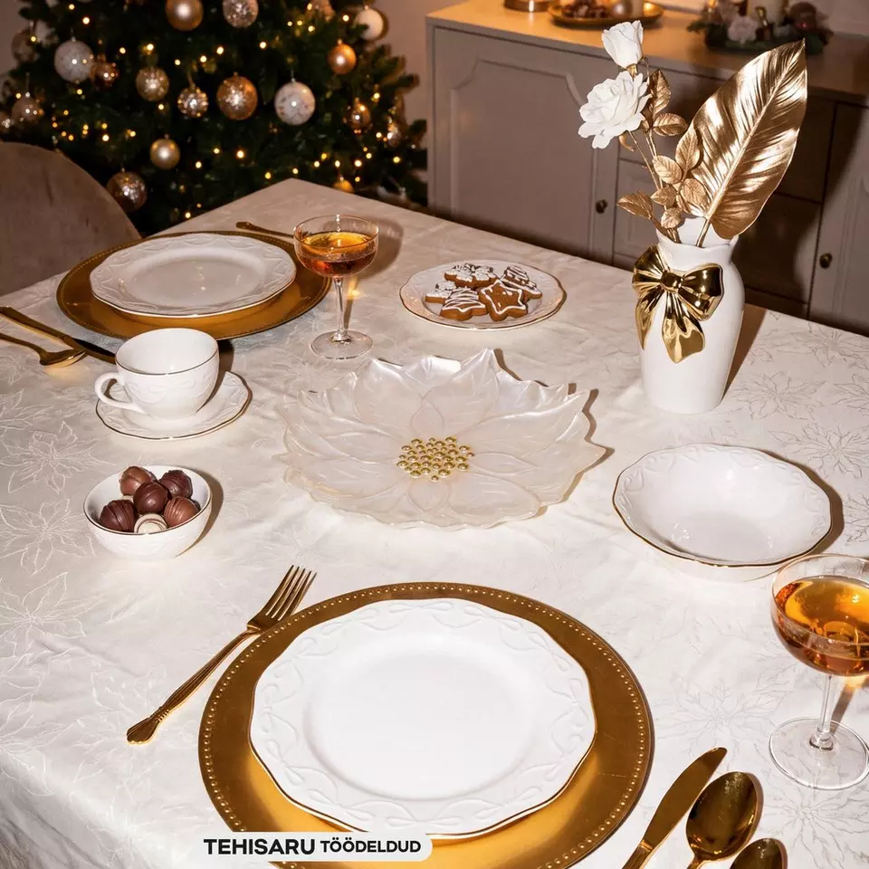 Pepco festive table setting with gold and white dinnerware, gingerbread biscuits, and Christmas tree in background.