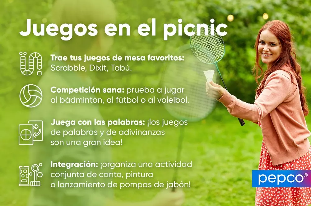 Mujer pelirroja sonriente sostiene raqueta de bádminton y volante en un picnic al aire libre.