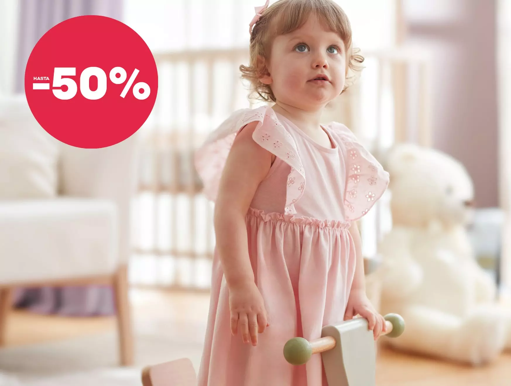 Niña pequeña con vestido rosa de Pepco mirando hacia arriba, promoción de hasta -50%.