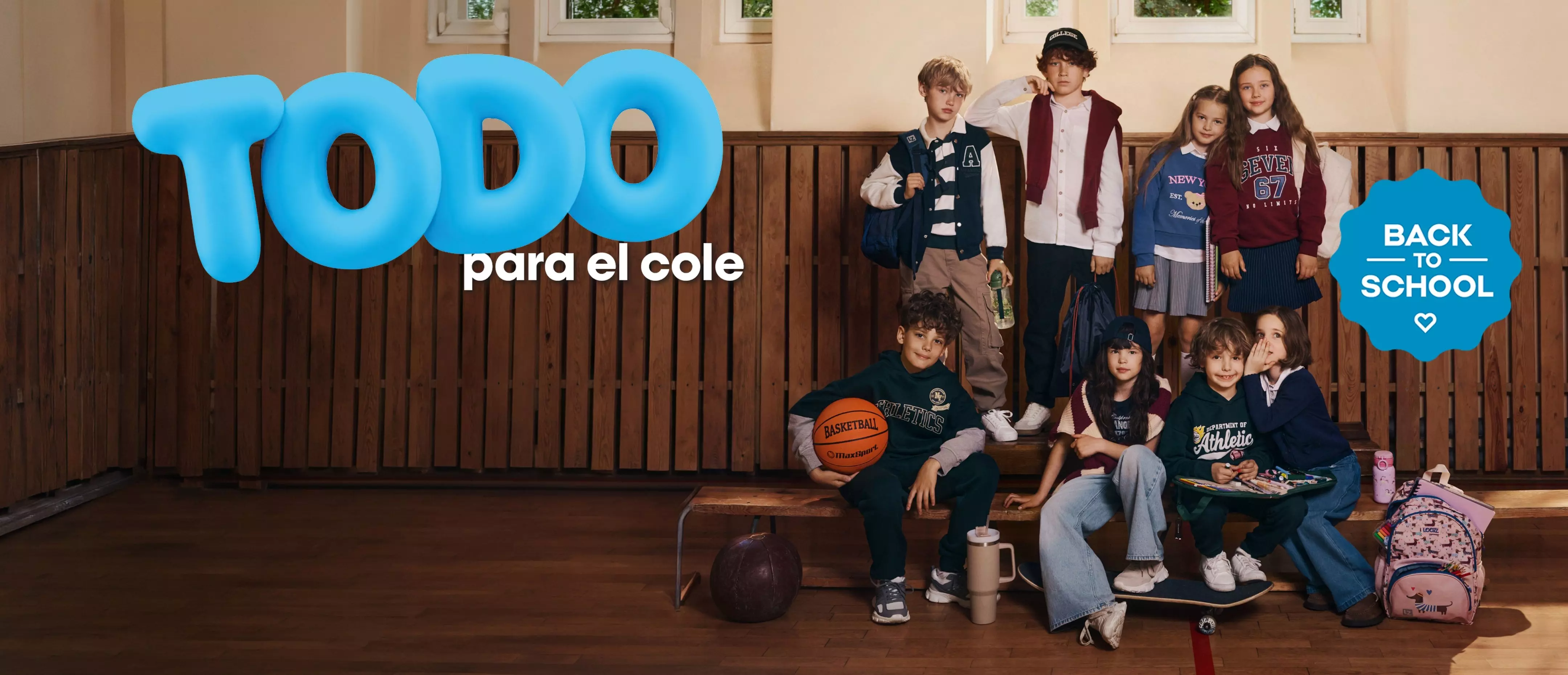 Niños con ropa escolar Pepco y mochilas en un gimnasio bajo el letrero TODO para el cole BACK TO SCHOOL.