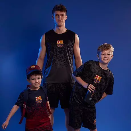 Egy felnőtt és két gyermek FC Barcelona logós sportruházatban pózol.