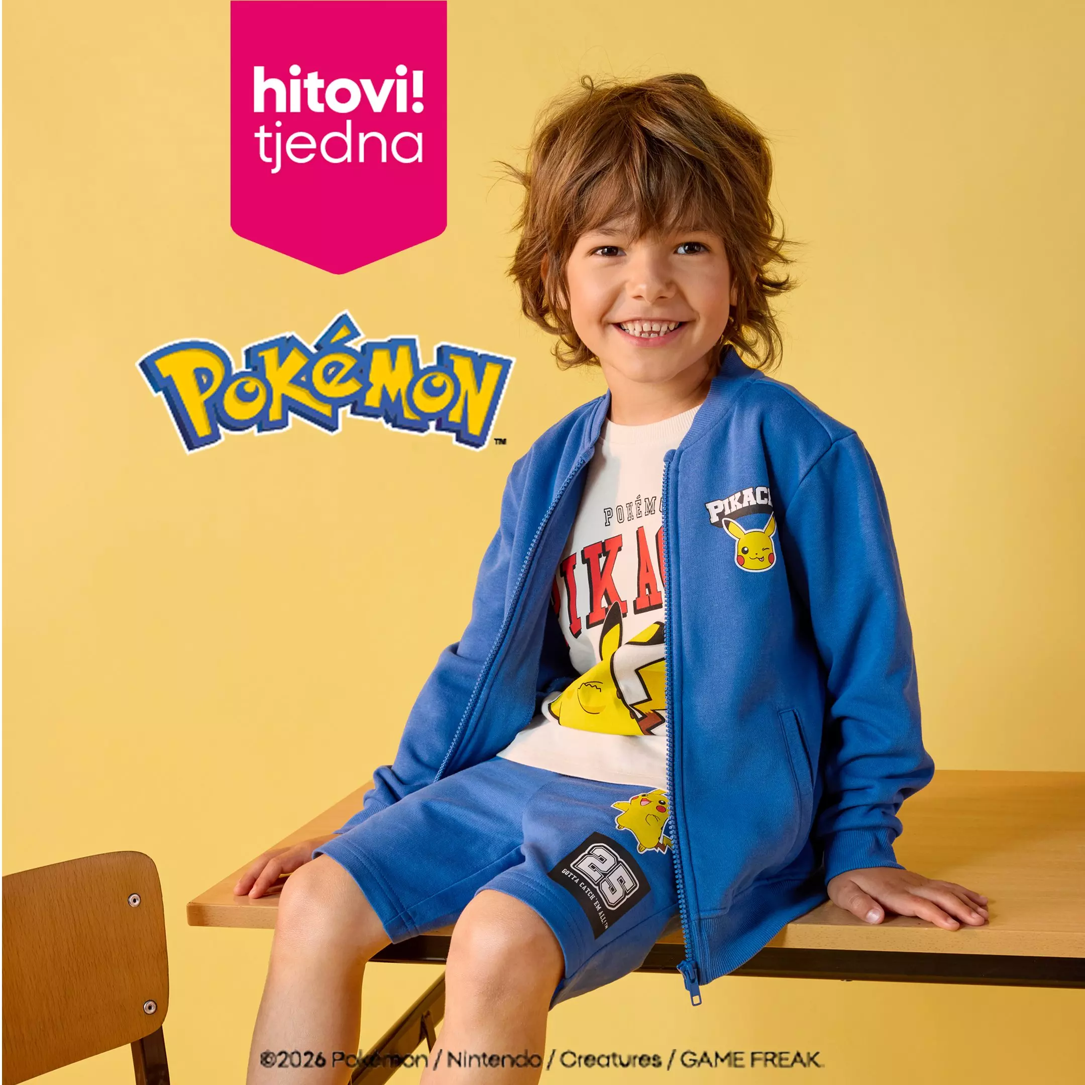 Dječak u Pepco Pokémon trenirci plave boje s Pikachuom sjedi i smiješi se.