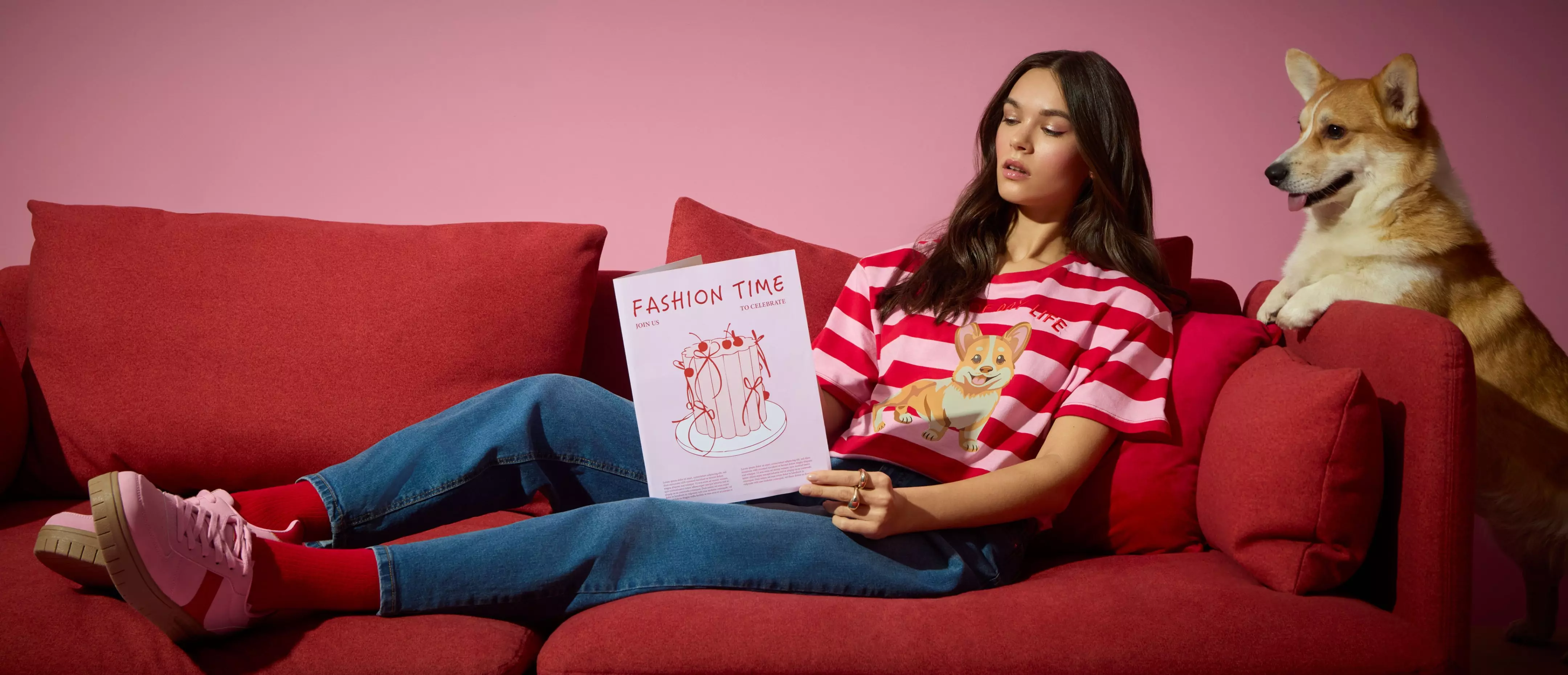 Kobieta w pasiastej bluzie Pepco z motywem psa czyta magazyn FASHION TIME, siedząc na czerwonej kanapie obok prawdziwego psa.