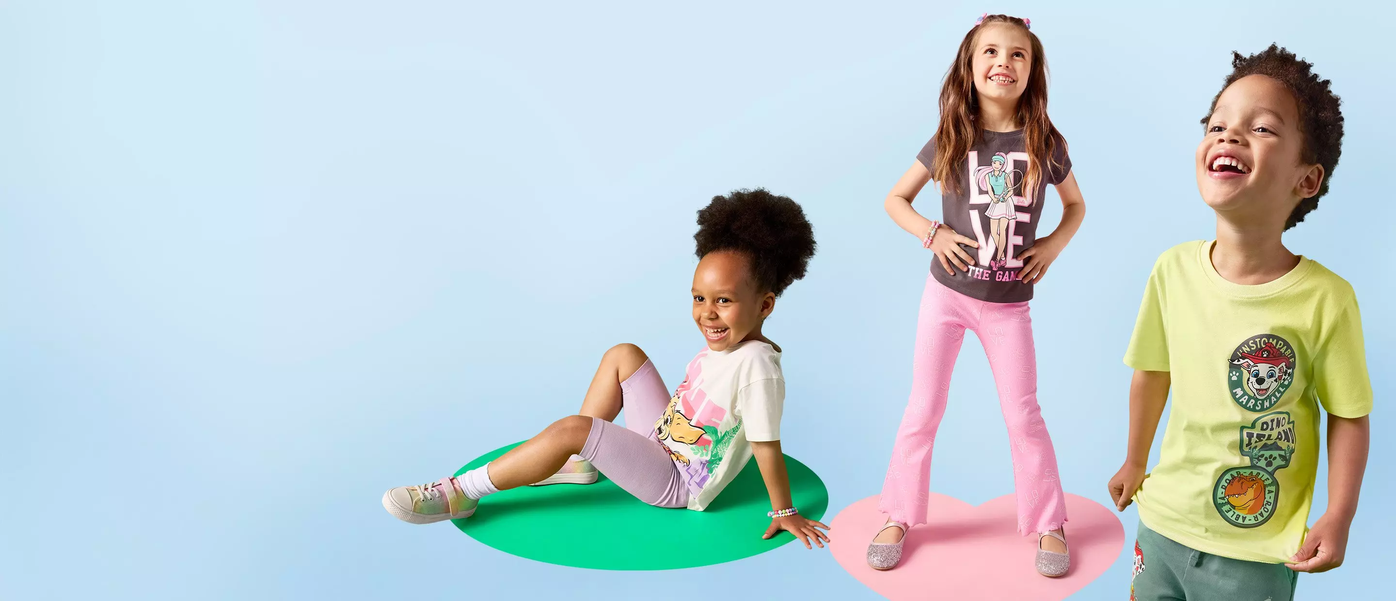 Tres niños sonrientes vistiendo camisetas con estampados de Pepco sobre círculos coloridos.