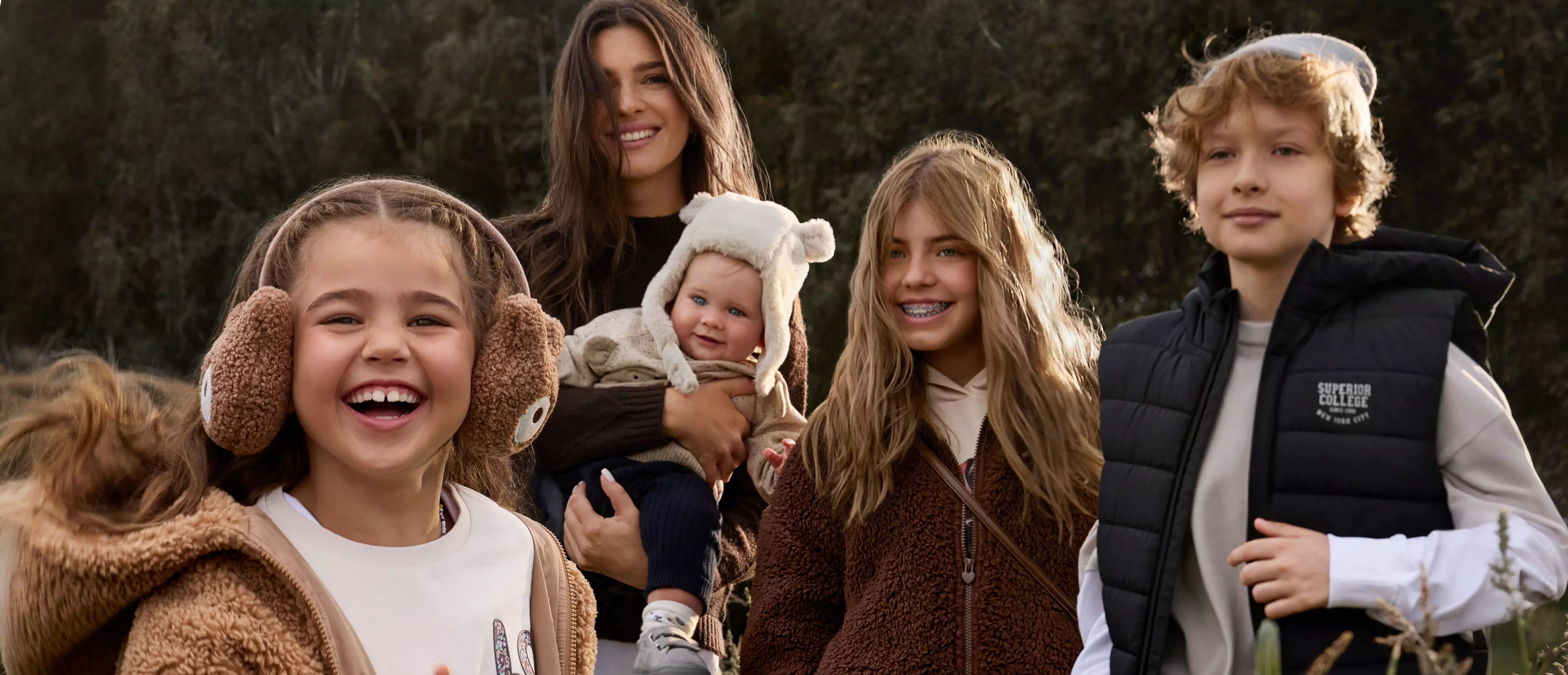 Pepco family wearing cosy winter clothing including fleece jackets and teddy bear ear accessories outdoors.