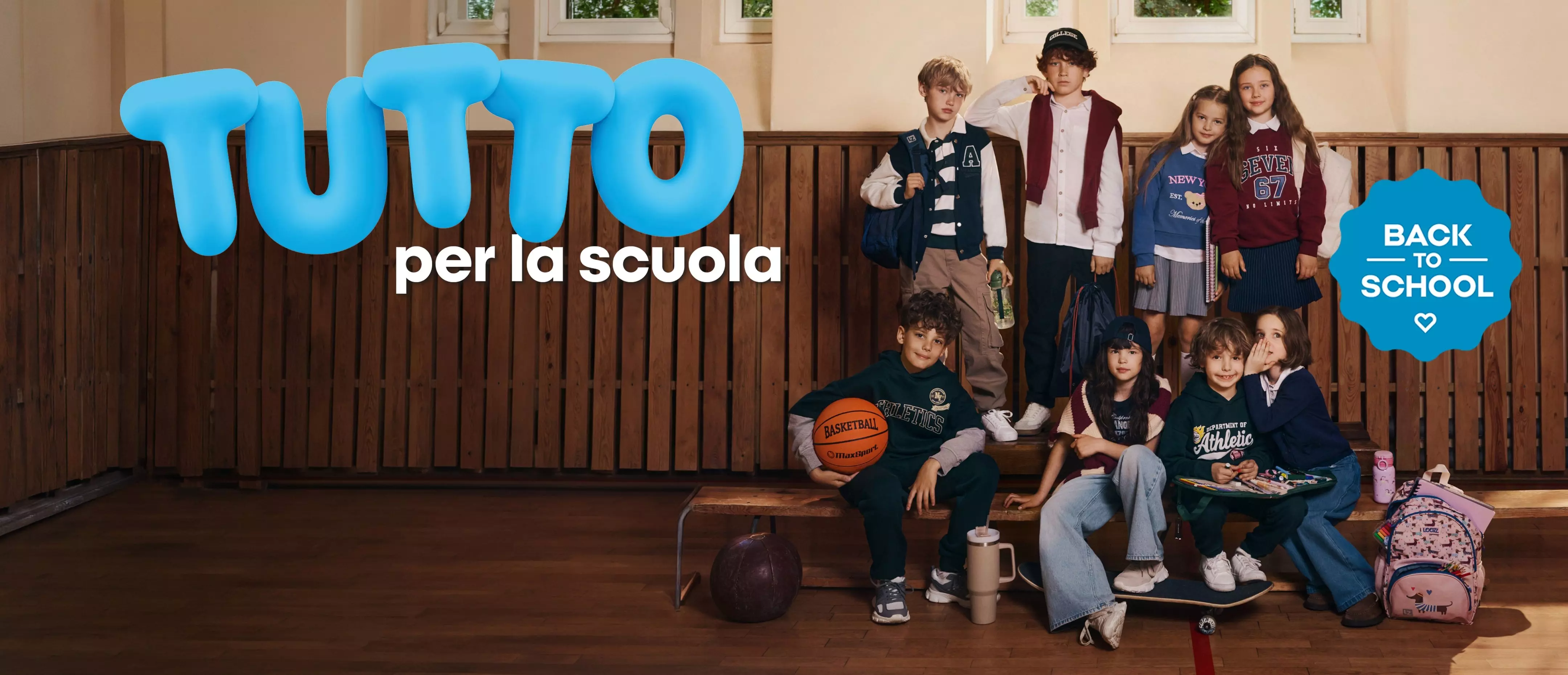 Bambini Pepco in abbigliamento scolastico casual posano su panchina con zaini e pallone da basket.