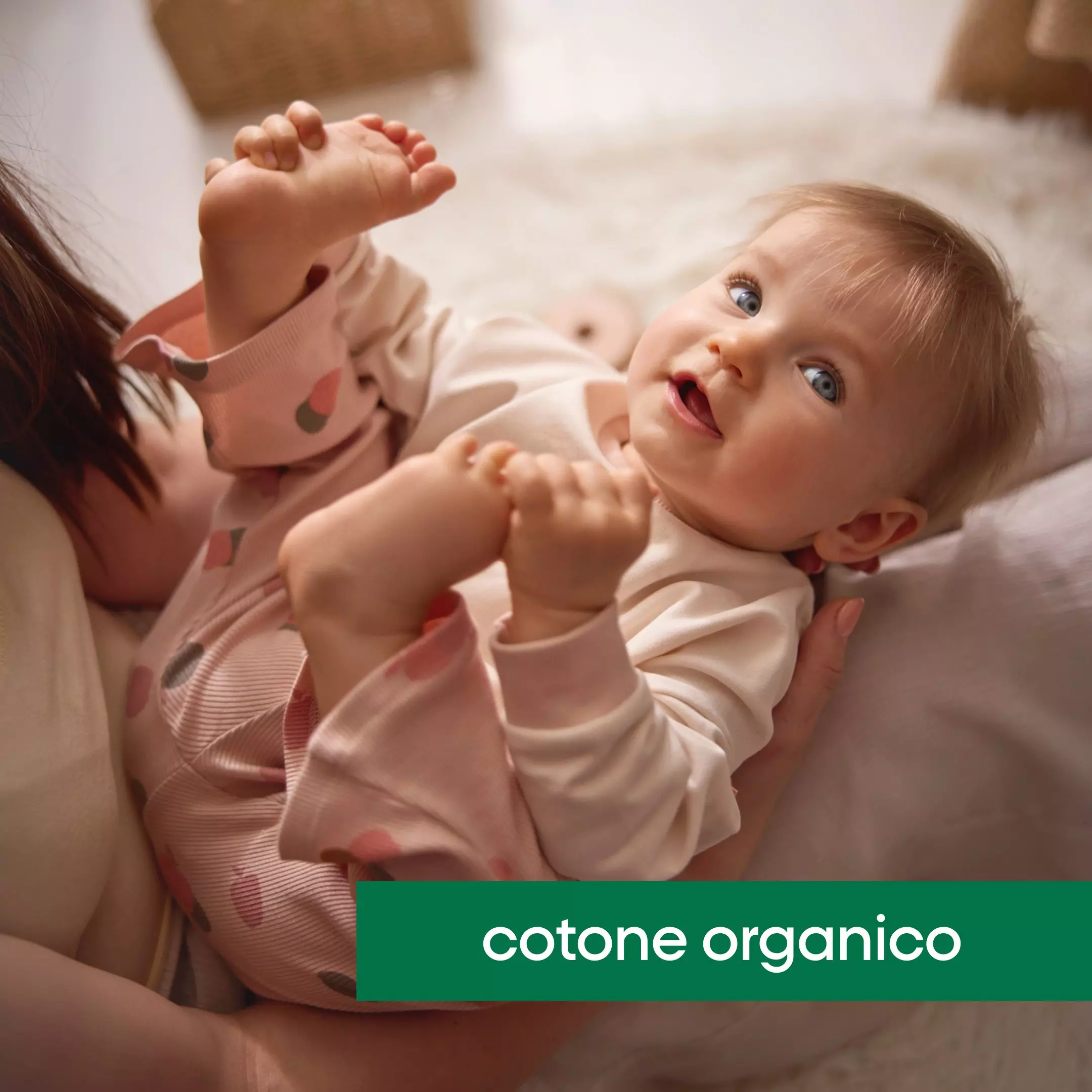 Neonata sorridente indossa abbigliamento Pepco in cotone organico rosa mentre gioca con la mamma.