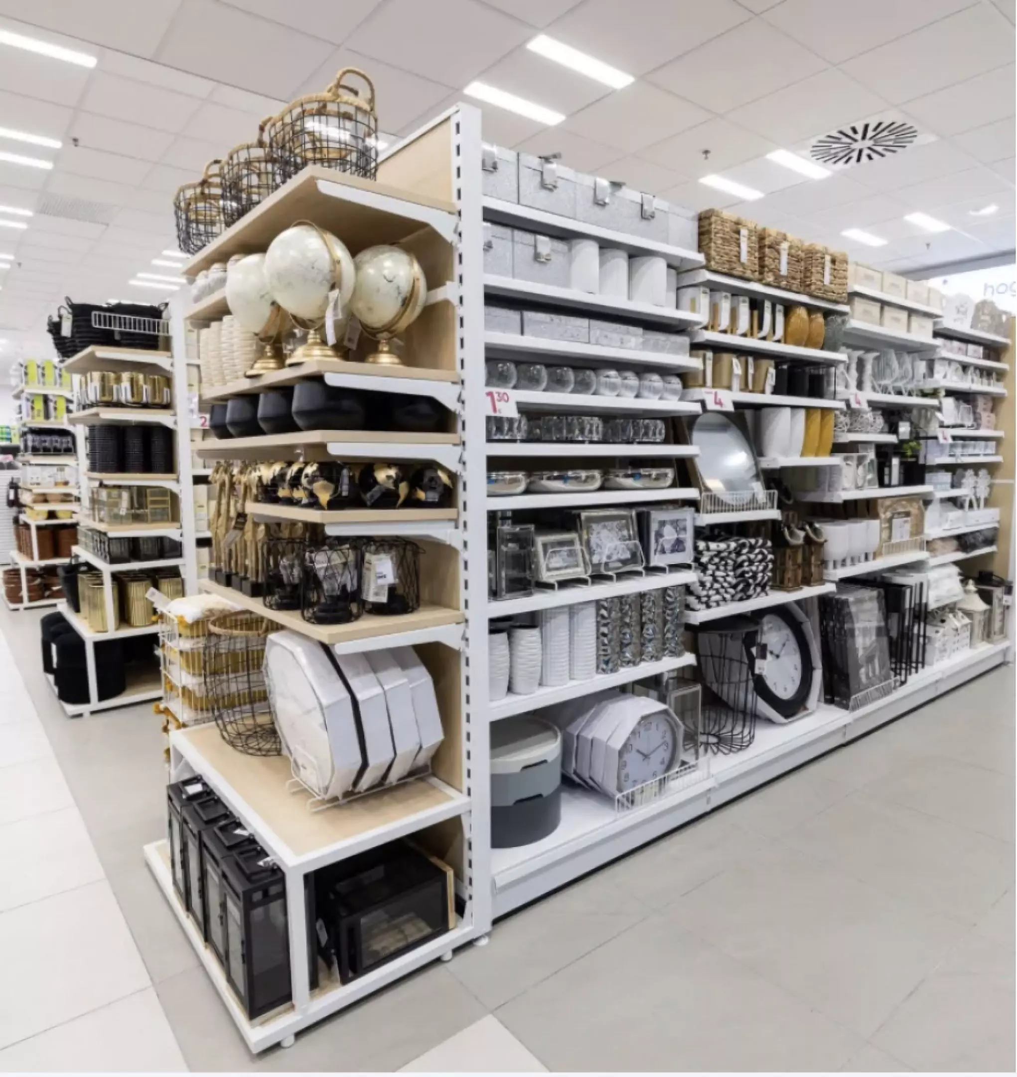 Pepco store shelves displaying home decor items including storage baskets, frames, clocks, and kitchenware in neutral colors.