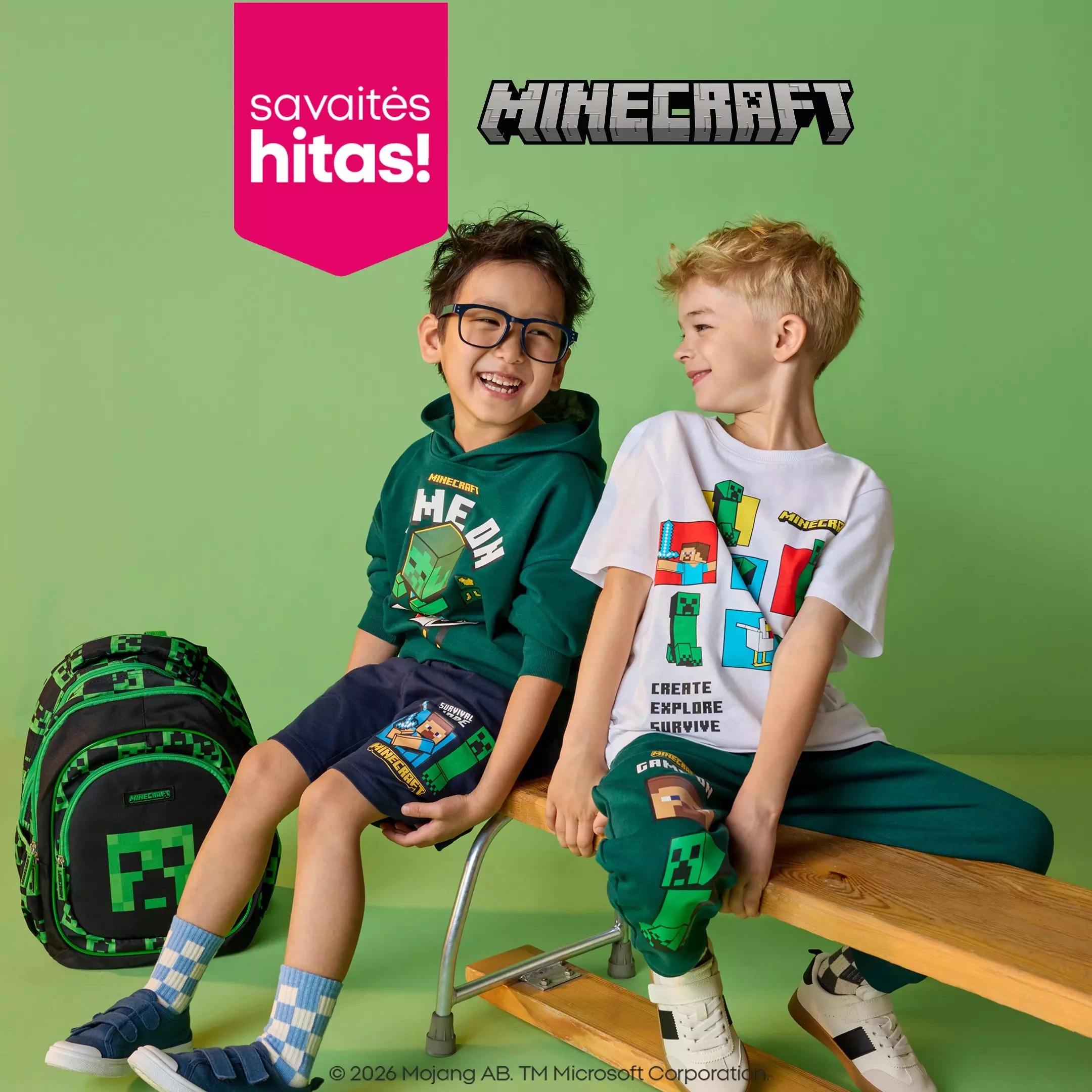Du berniukai dėvi Pepco Minecraft drabužius ir šypsosi sėdėdami ant suolelio su Minecraft kuprine.