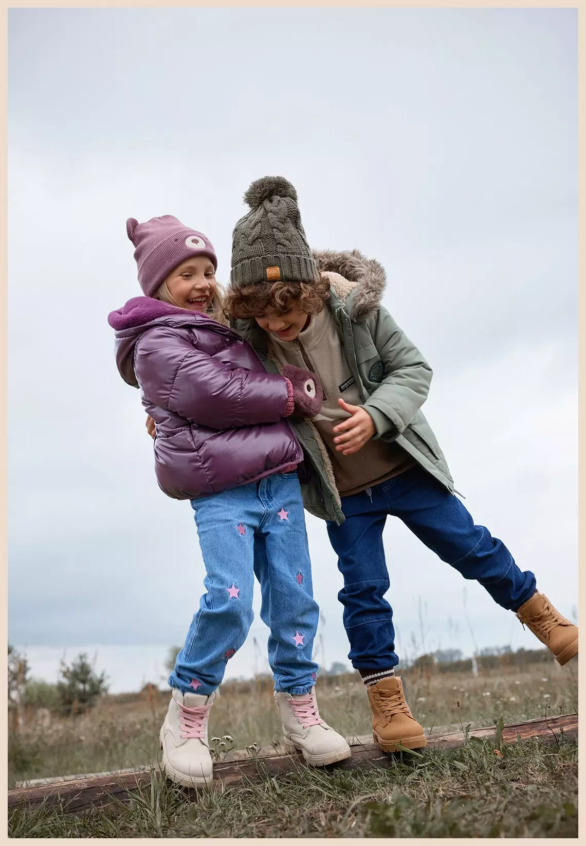 Dos niños jugando al aire libre con ropa de invierno Pepco, incluyendo chaquetas acolchadas, gorros y vaqueros.