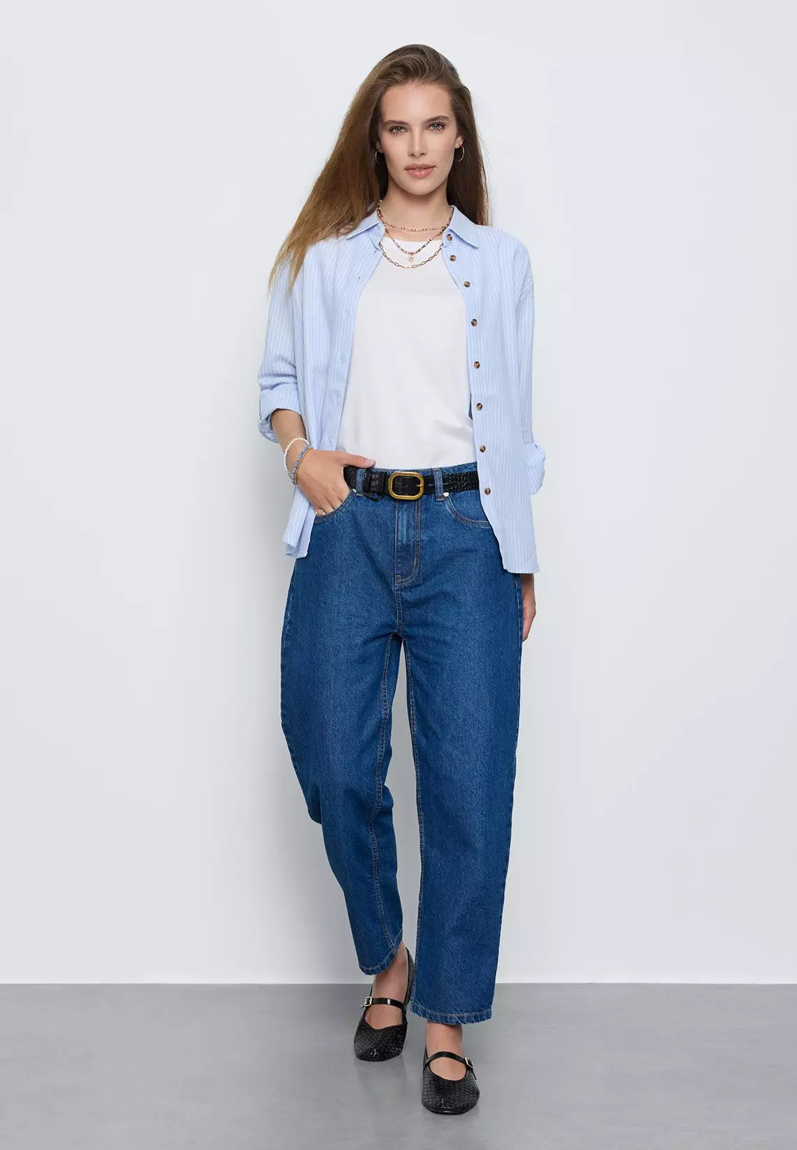 Pepco woman wearing blue striped shirt, white top, blue jeans with black belt and layered necklaces.
