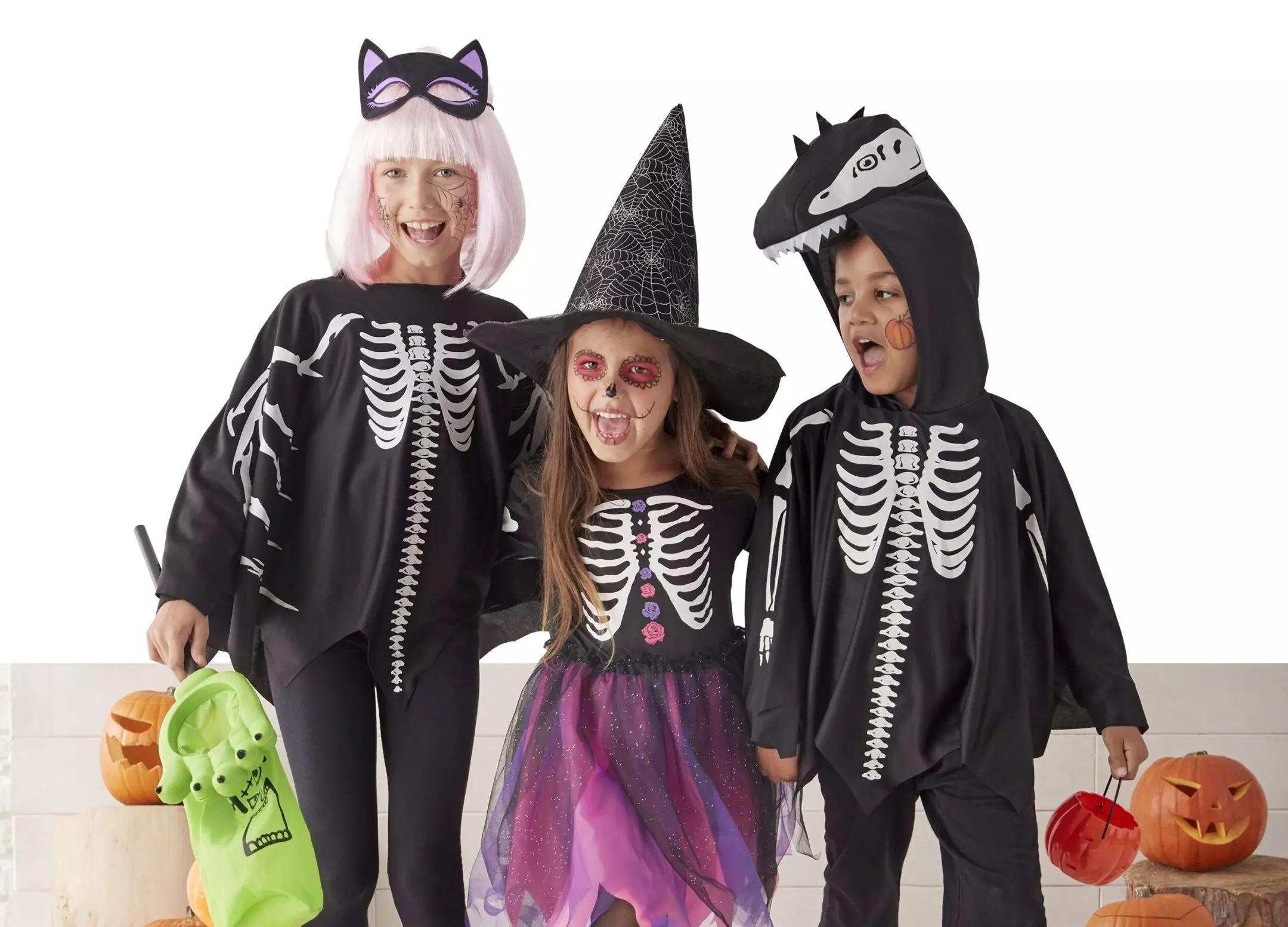 Dzieci w kostiumach halloweenowych od Pepco - szkielet z maską kota, czarownica i szkielet z kapturem dinozaura.