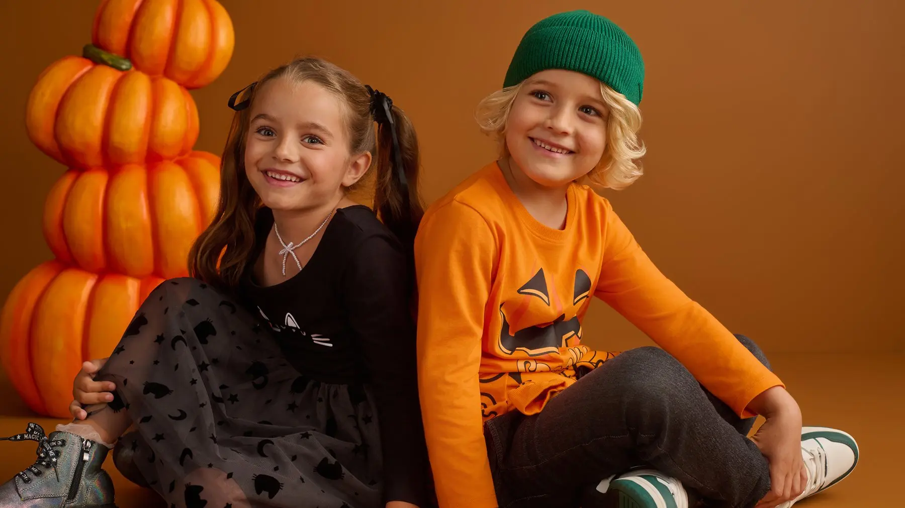 Pepco children wearing Halloween-themed outfits posing together with decorative pumpkins.