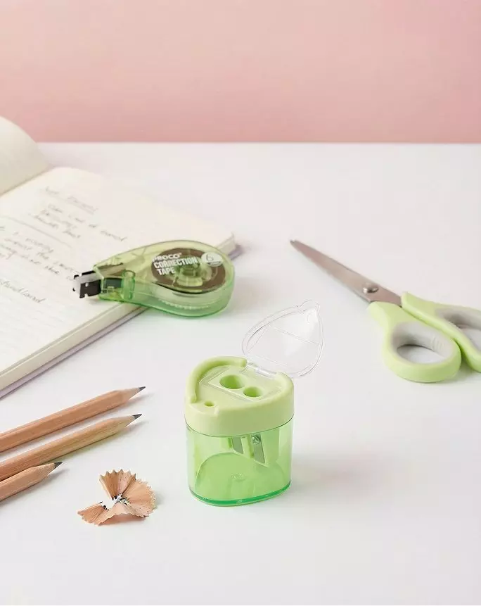 Pepco green stationery set including pencil sharpener, correction tape, scissors and pencils on white surface.