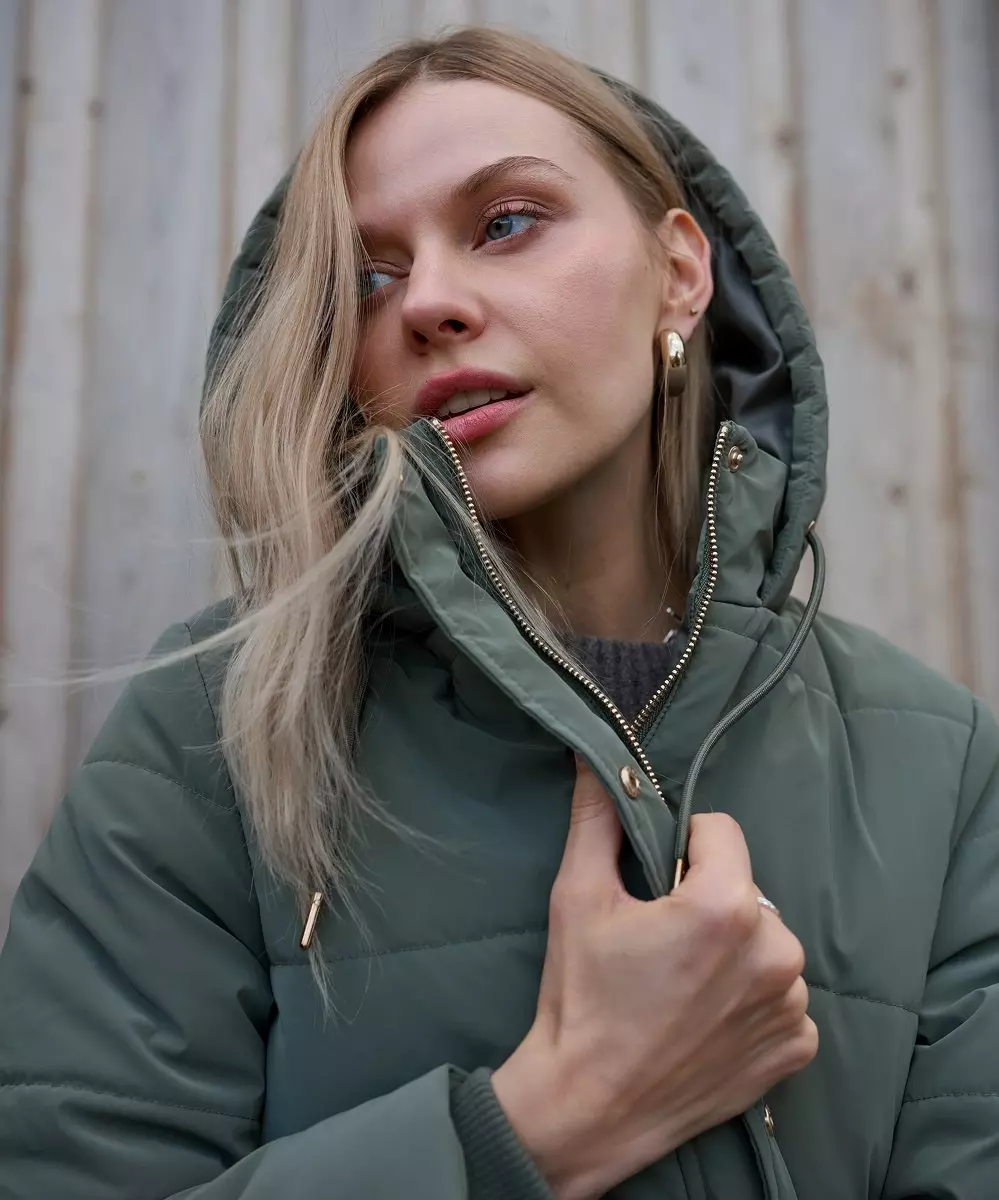 Woman wearing Pepco green quilted puffer jacket with hood and gold zip detail.