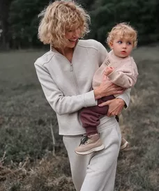 Pepco donna in tuta tiene in braccio un bimbo con felpa e pantaloni.