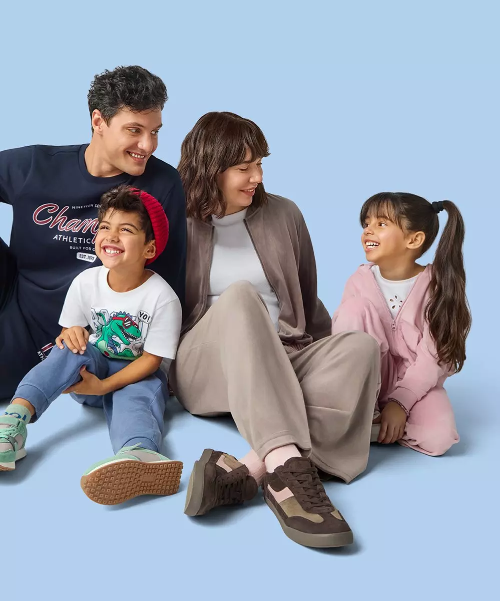 Family sitting together wearing casual clothing including Champion t-shirt, dinosaur print shirt, and pink jacket.