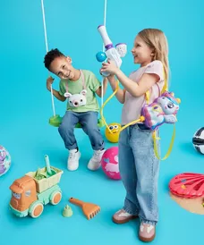 Two children playing with colourful outdoor toys including swings, fishing rods, and sand toys.