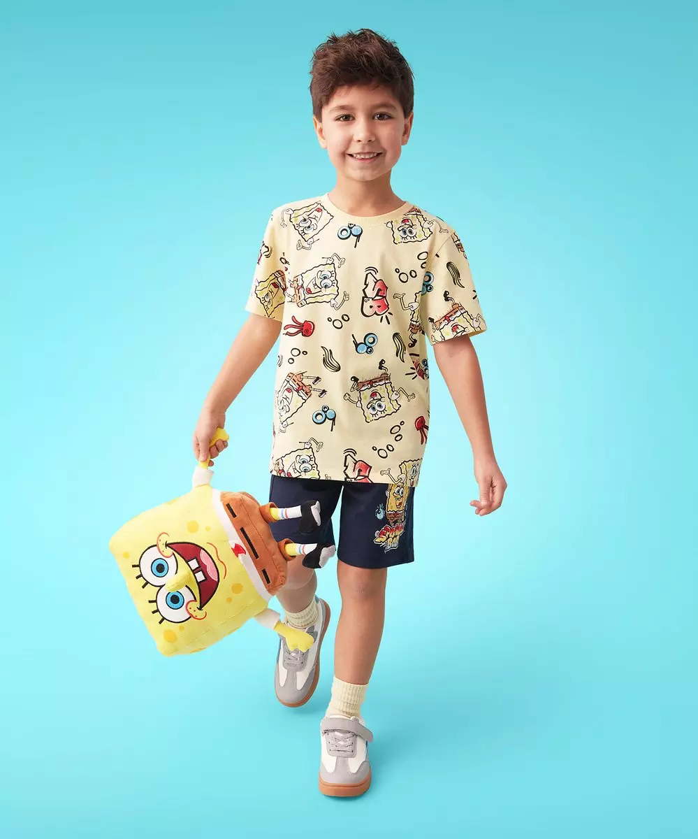 Boy wearing SpongeBob SquarePants printed t-shirt and shorts set, holding character plush toy.