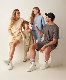 Rodina v pastelových tričkách a šortkách, dítě a dívka dávají high-five.