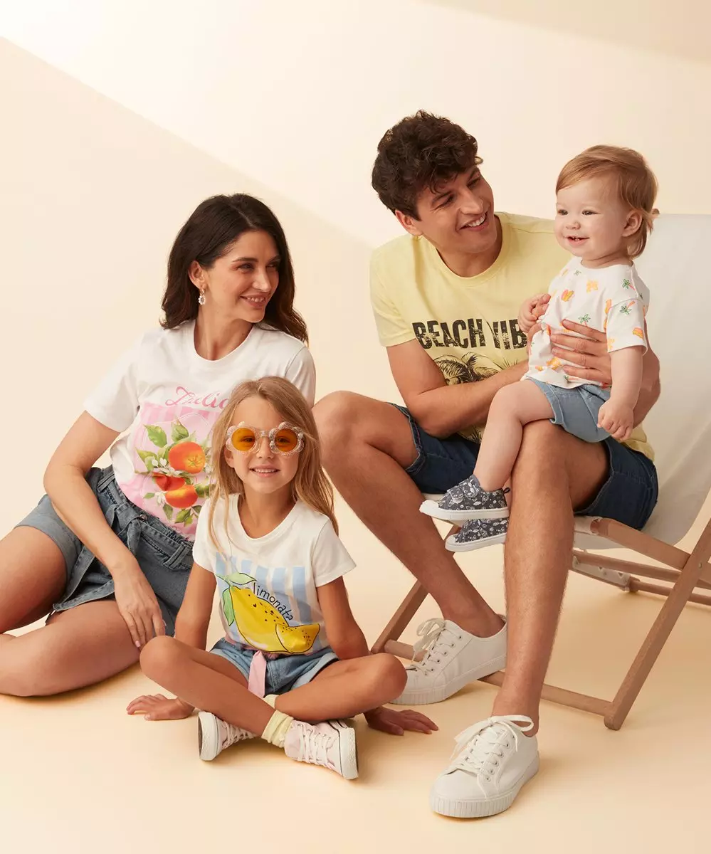 Rodzina w letnich t-shirtach z nadrukami owocowymi i szortach dżinsowych, pozująca razem.