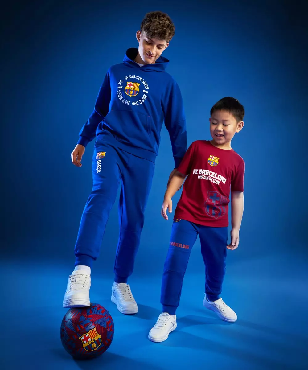 Dva dečka v Pepco FC Barcelona športni obleki se igrata z žogo.