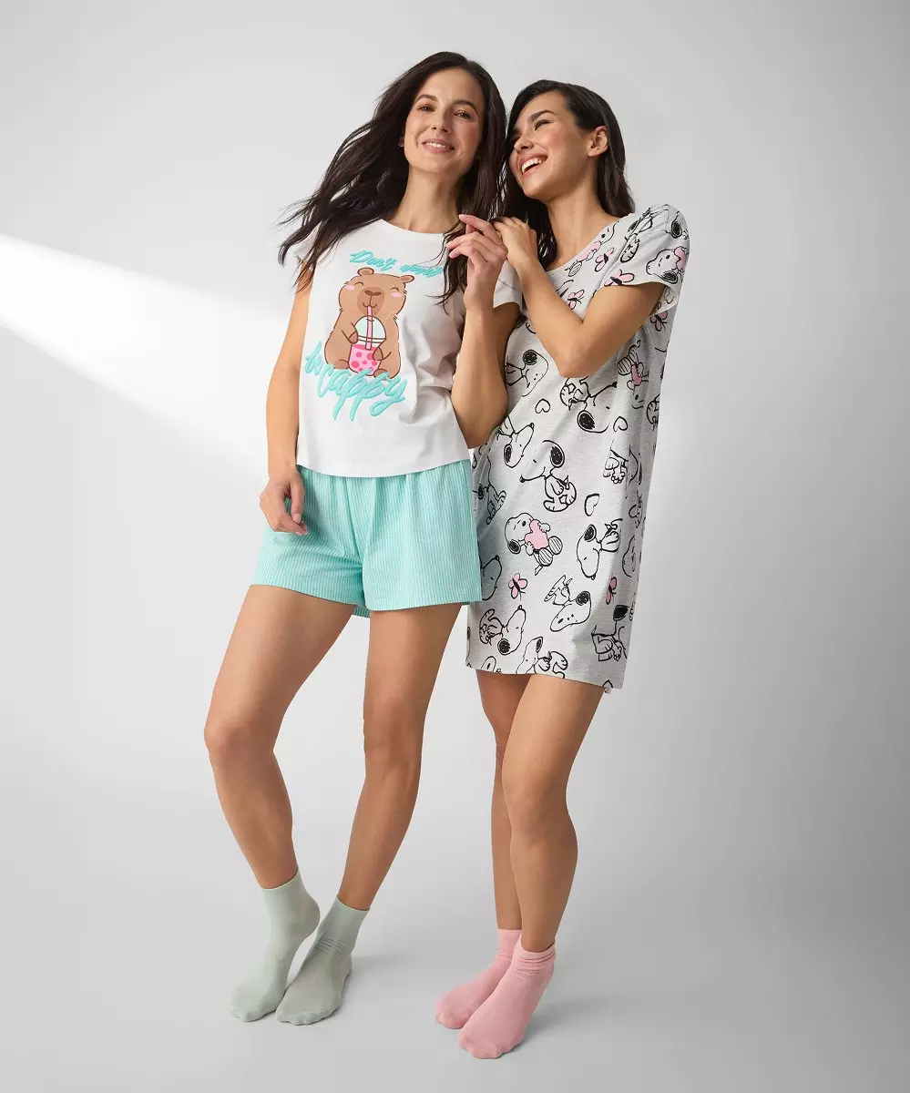 Dos mujeres sonrientes vistiendo pijamas de verano con estampados divertidos y calcetines de colores.