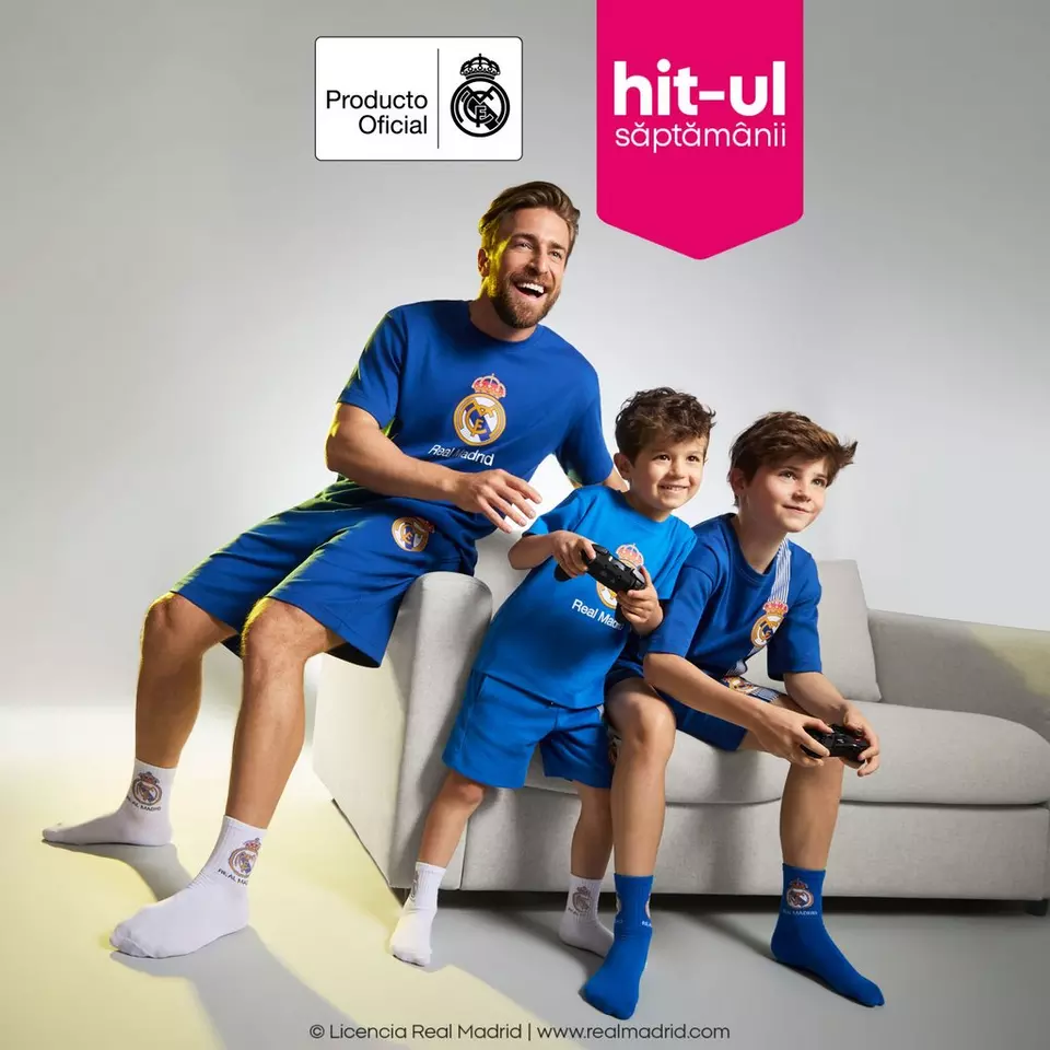 Tată și doi băieți purtând echipamente oficiale Real Madrid de la Pepco, jucând jocuri video pe canapea.