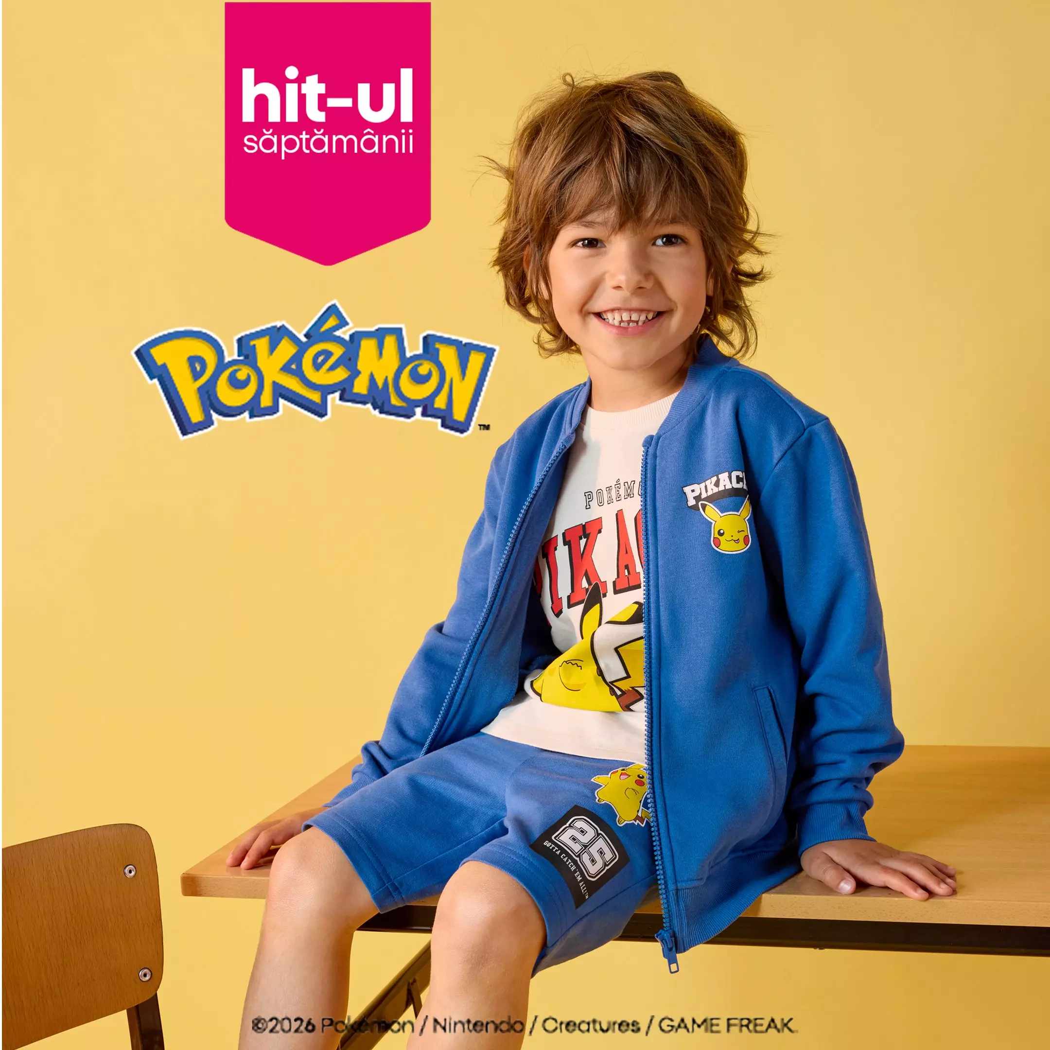 Băiat zâmbitor purtând trening albastru Pokémon de la Pepco, șezând pe o bancă.