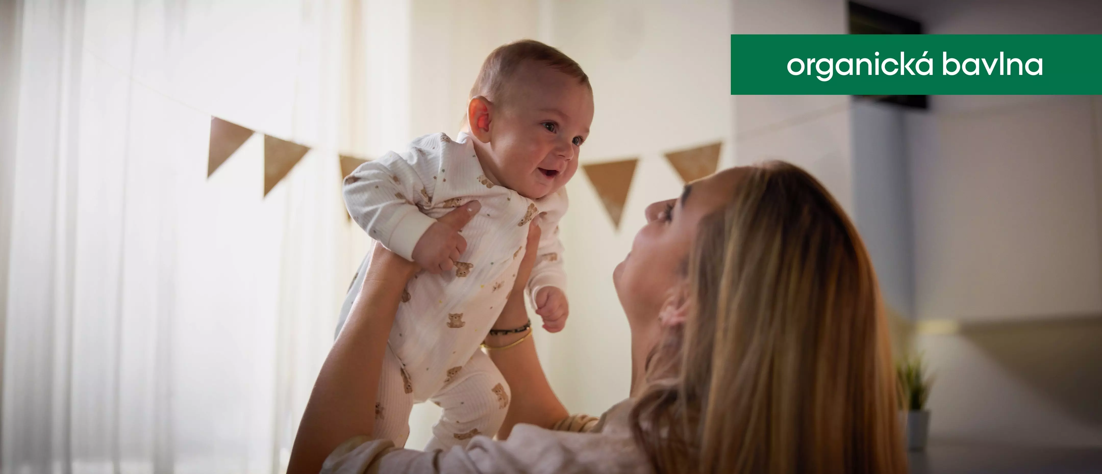 Pepco organická bavlna - mama drží usmievajúce sa bábätko v pyžame s medvedíkmi.