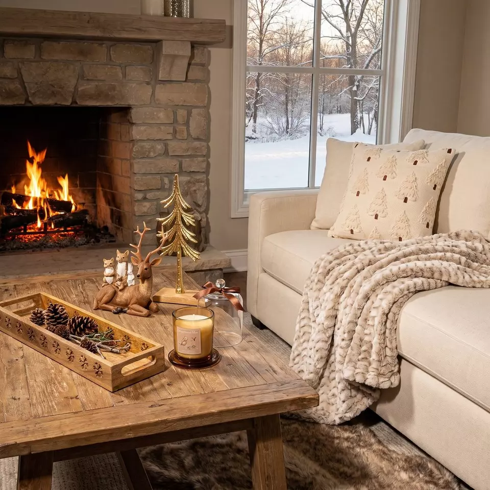 Pepco cosy living room with lit fireplace, cream sofa with festive cushions, chunky throw and Christmas decorations.