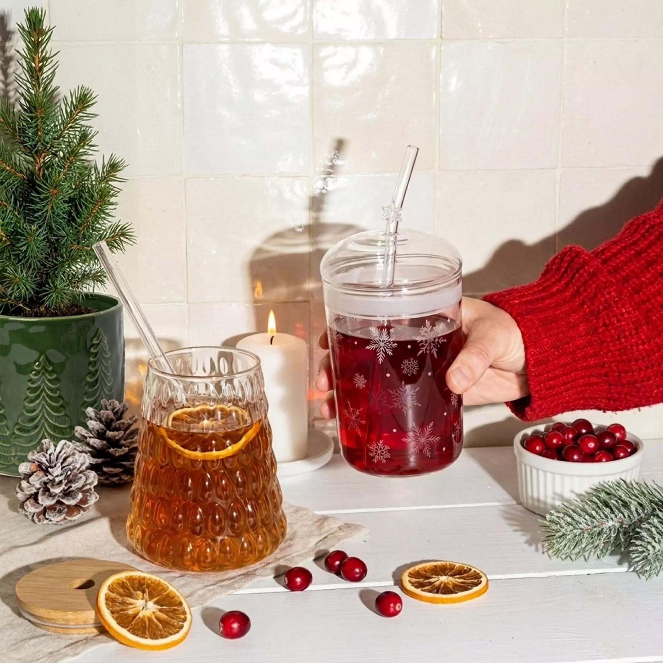 Vajilla navideña Pepco con vaso decorado con copos de nieve, vela encendida y decoración festiva con piñas.