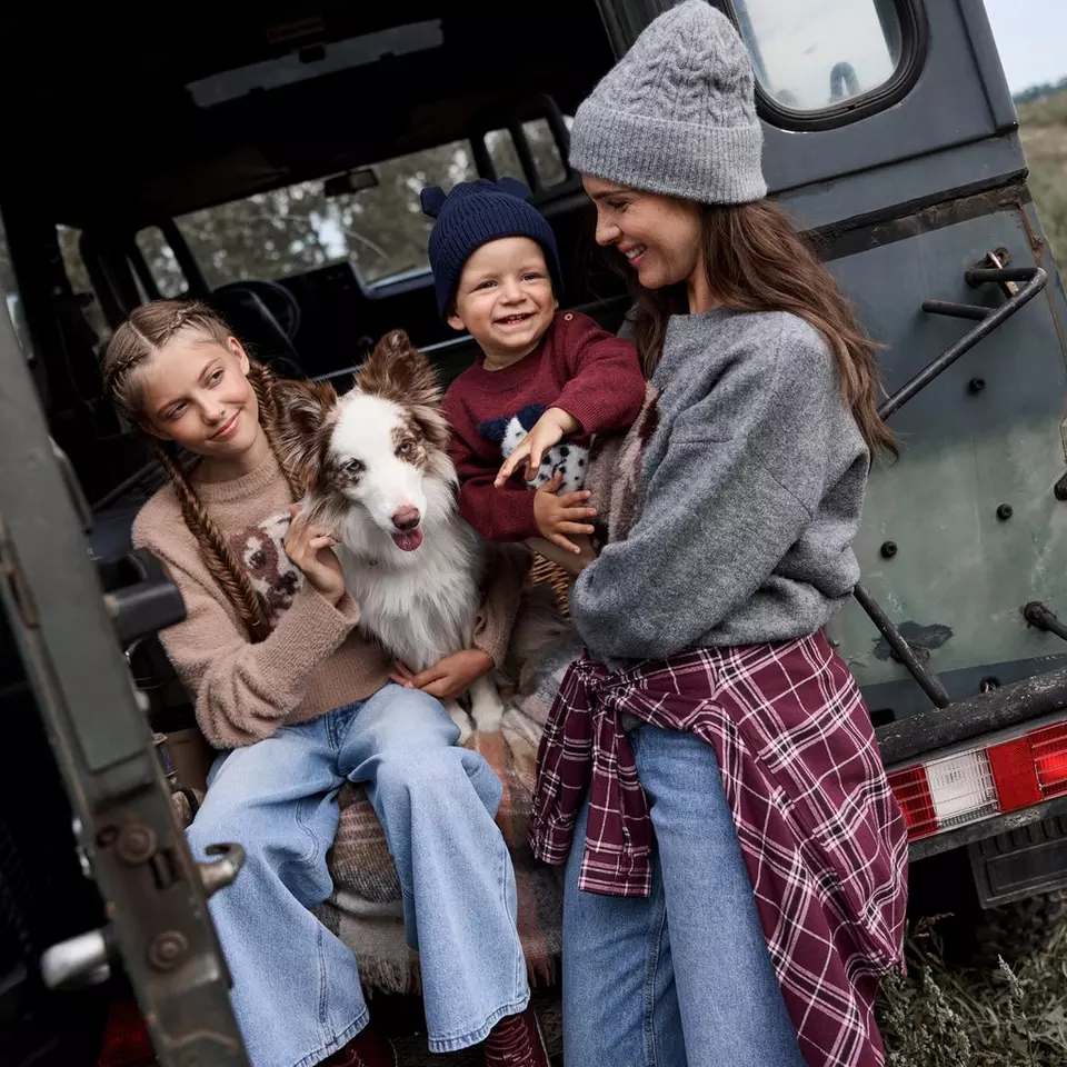 Familia Pepco disfrutando de un día al aire libre con su perro junto a una furgoneta vintage.
