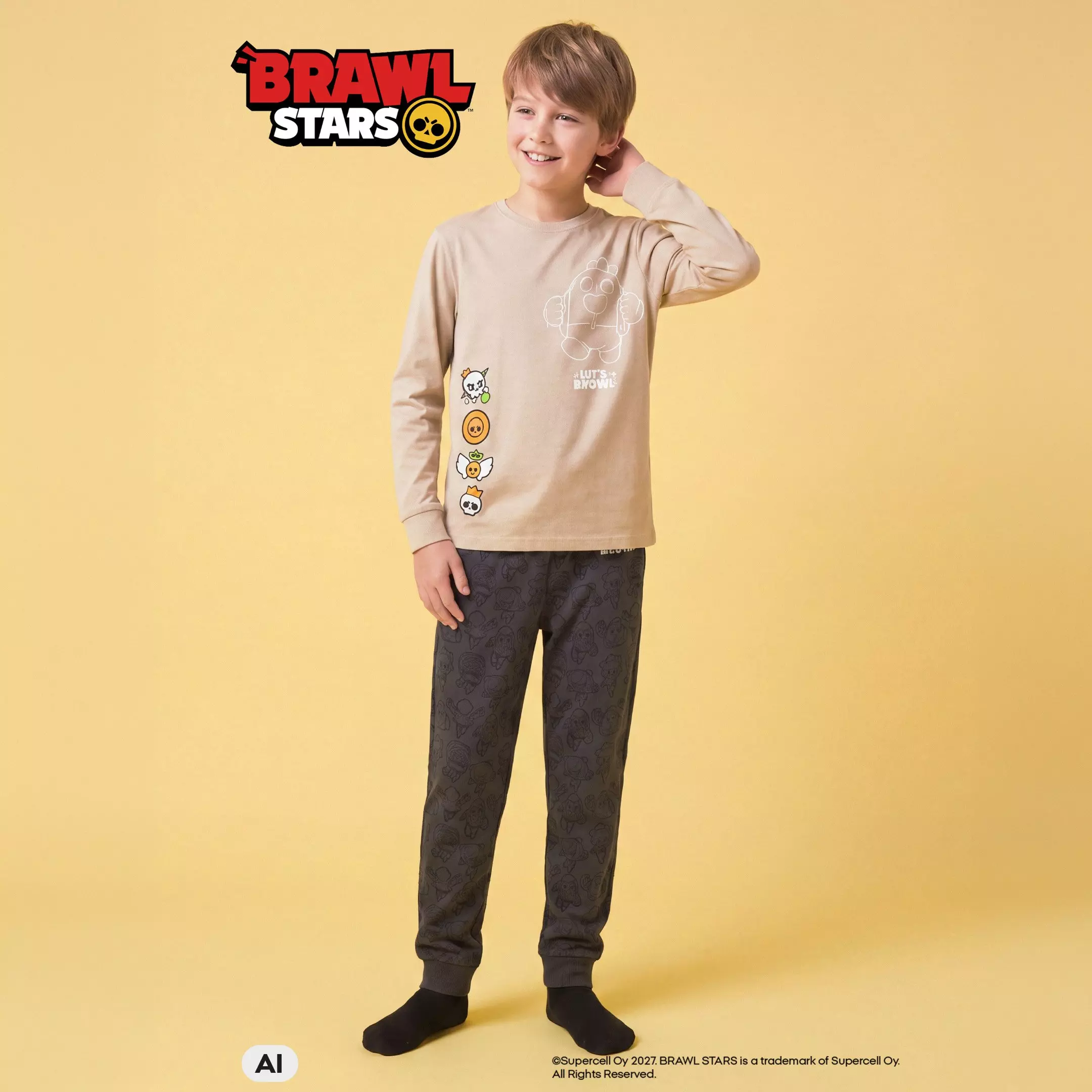 Pepco pijama pentru băieți Brawl Stars, bluză bej și pantaloni gri cu imprimeu, purtată de un copil.