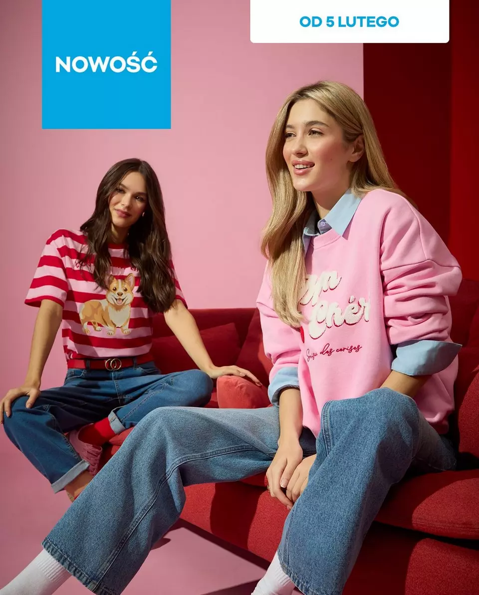 Dwie osoby na czerwonej kanapie w dżinsach - jedna w różowej bluzie, druga w pasiastej koszulce z nadrukiem corgi. Napis "NOWOŚĆ" i "OD 5 LUTEGO".