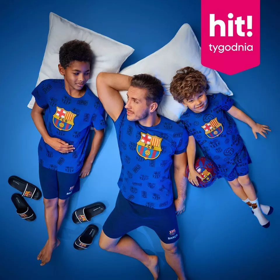 Trzech modeli w niebieskich piżamach FC Barcelona leży na poduszkach, obok klapki z logo klubu i piłka.