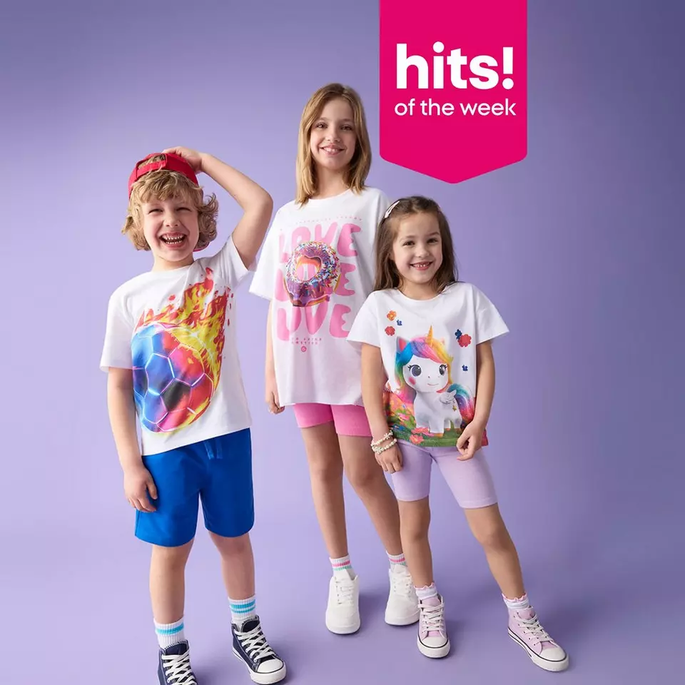 Three children wearing colourful graphic t-shirts with football, donut, and unicorn designs.