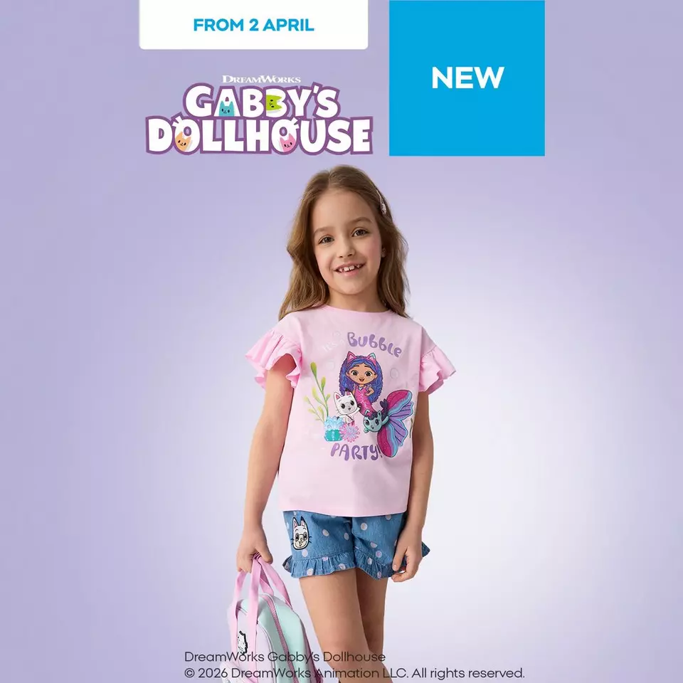 Girl wearing pink Gabby's Dollhouse t-shirt with Bubble Party graphic and denim shorts, smiling.