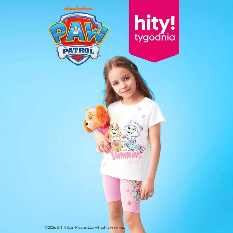 Dziewczynka w białej koszulce i różowych szortach z motywem Psi Patrol, trzymająca pluszową zabawkę.