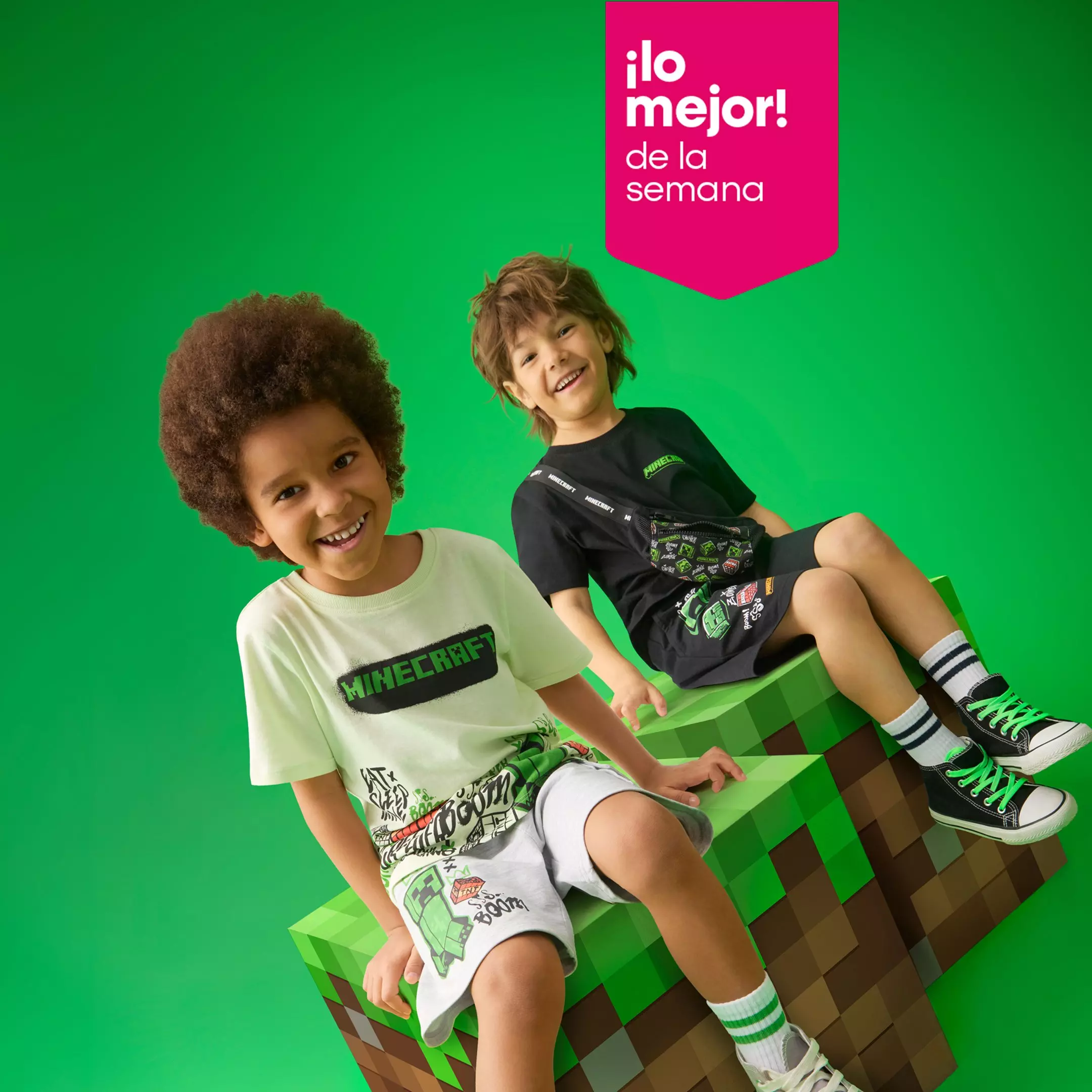 Dos niños sonrientes vistiendo ropa de Minecraft sentados sobre bloques decorativos del juego.