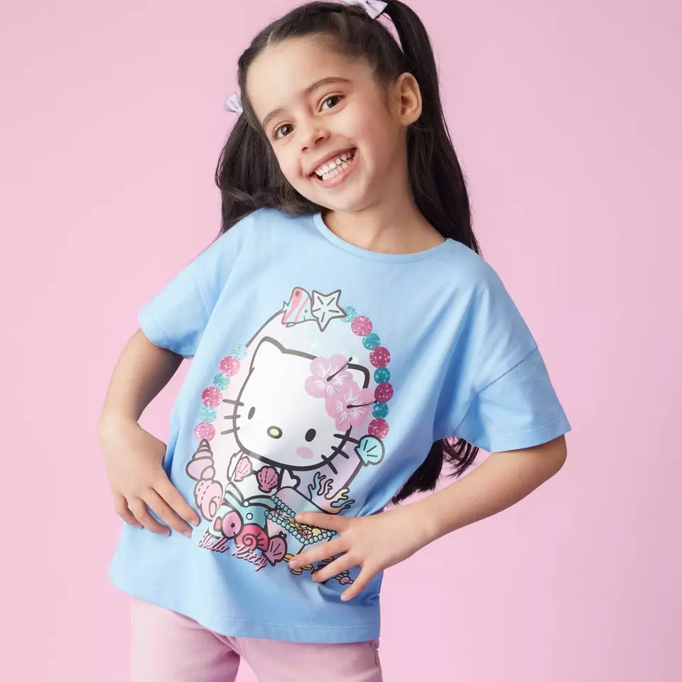 Dekle v Pepco modri majici s Hello Kitty potiskom se nasmehne v kamero.