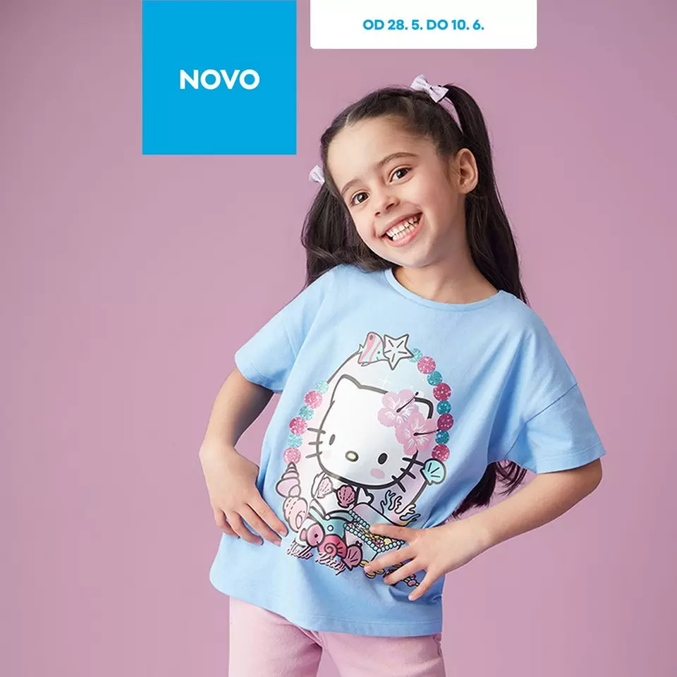 Deklica se nasmihuje v svetlo modri majici Hello Kitty s pentljami v laseh pri Pepco.