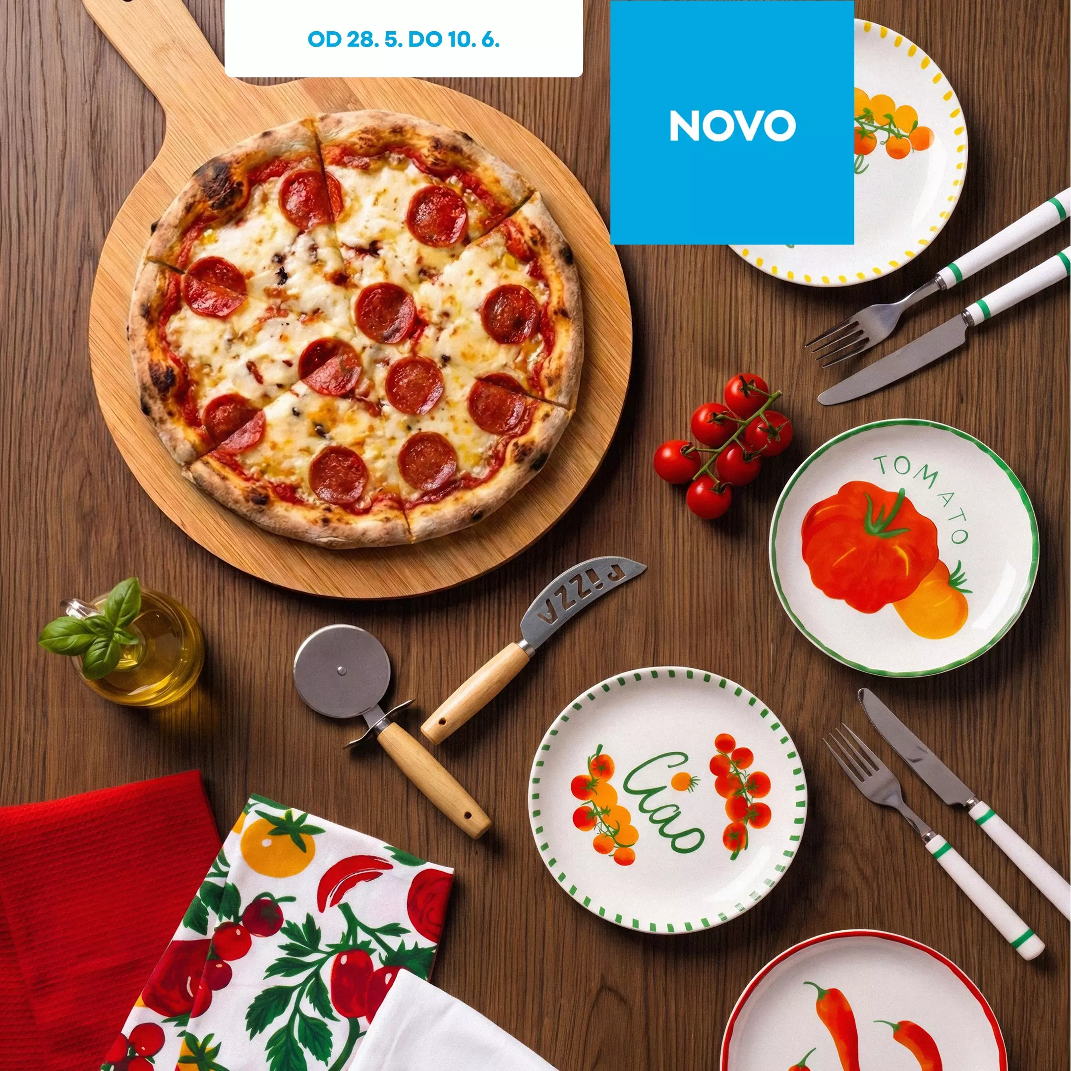 Pepco pizza s peperonijem na drvenoj dasci s dekorativnim tanjurima, priborom za jelo i pizza rezačem.