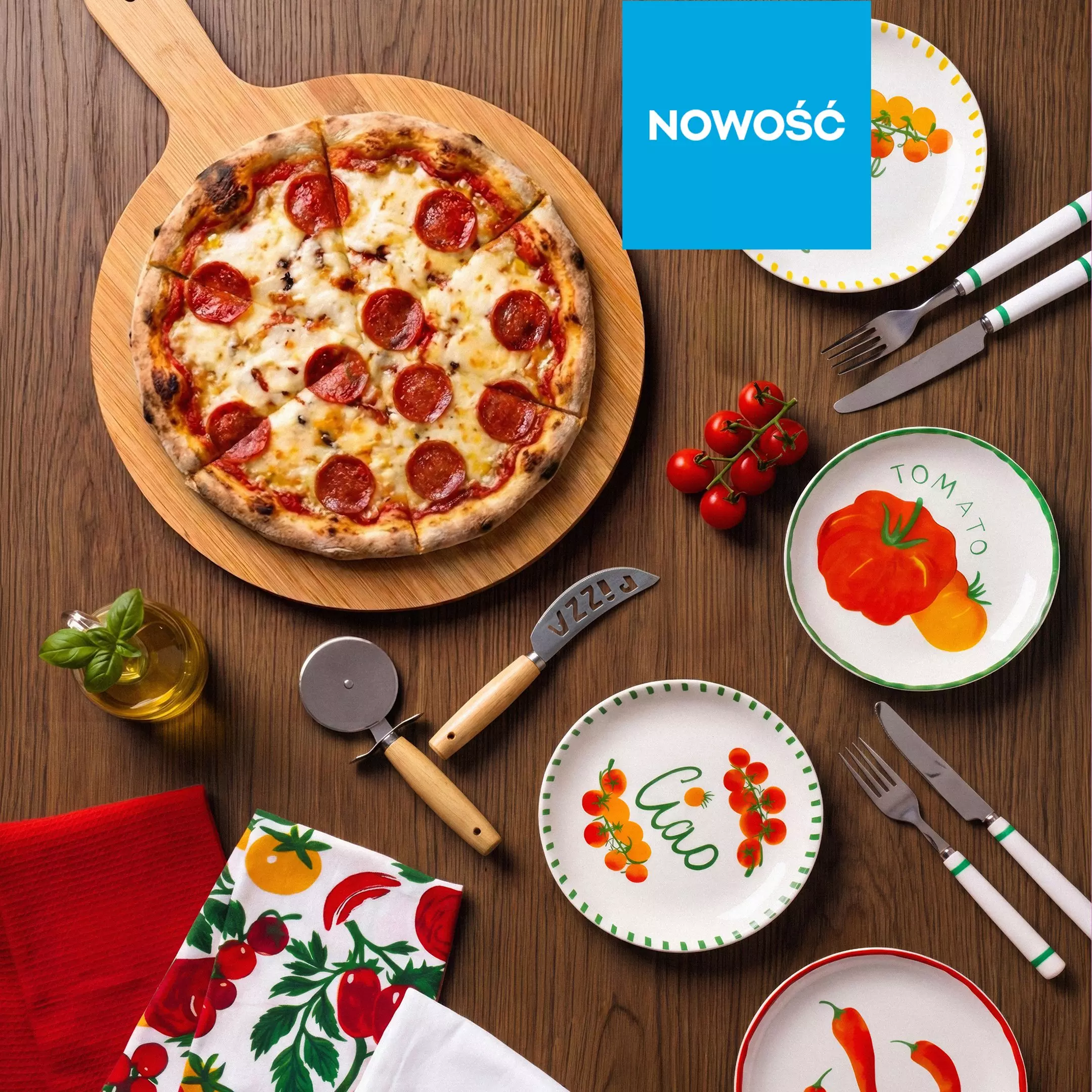 Pizza pepperoni na drewnianej desce z talerzami ozdobionymi warzywami i akcesoriami kuchennymi Pepco.